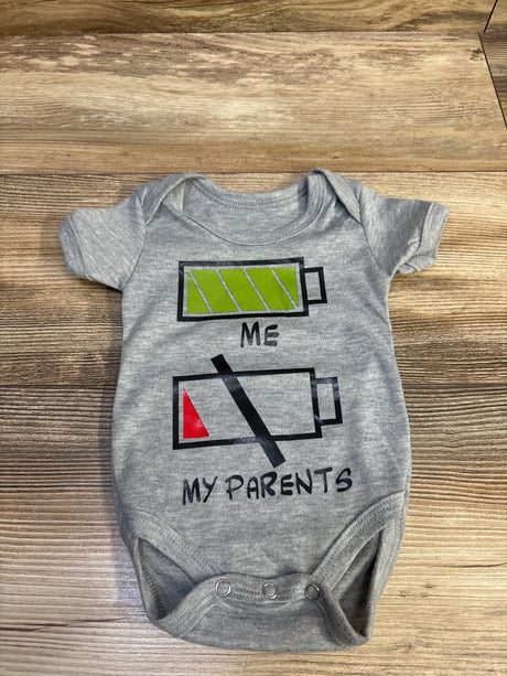 Front view of grey Battery bodysuit showcasing green and red battery graphics with the text ME and MY PARENTS on a wood surface