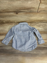 Long sleeve blue and white striped button-up toddler shirt on wood background