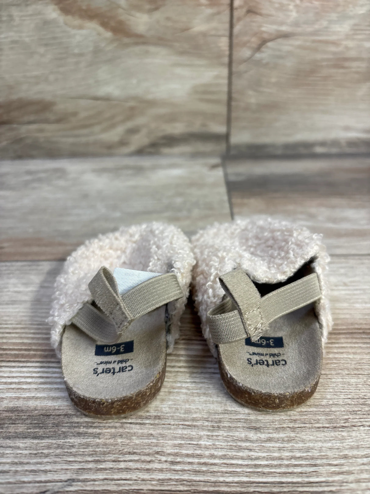 Front view of Child of Mine slip-on clogs showcasing beige boucle upper and elastic heel straps with wood floor background