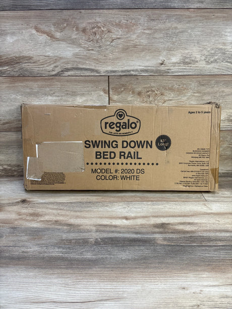 Front of boxed Regalo swing down bed rail showing large Swing Down Bed Rail label, 43 inch length and color white on wood-plank background