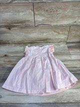 Front-flat view of pink eyelet toddler dress showcasing eyelet flutter sleeves and back button closure on light wood floor background