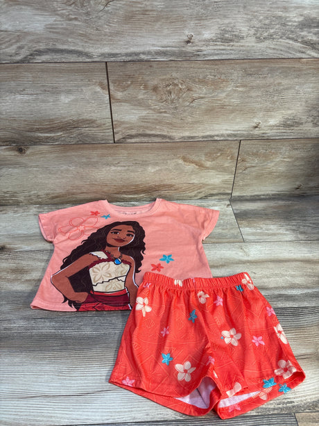Flat lay of Moana two-piece peach pajama set showing short-sleeve top with Moana print and floral elastic-waist shorts on wood floor