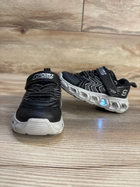 Black kids light-up sneakers with white soles and velcro straps on wood floor