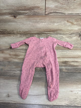 Pink footed baby sleeper with tiny heart pattern and zipper on wooden floor