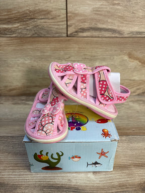 Pink toddler sandals with polka dot bow details on a kids shoe box, wooden background