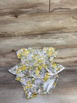 Flat-lay of Carter's floral skirted bodysuit, 3M, showcasing short sleeves, ruffle skirt and snap crotch on light wood floor