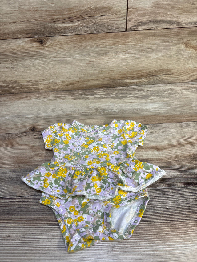 Flat-lay of Carter's floral skirted bodysuit, 3M, showcasing short sleeves, ruffle skirt and snap crotch on light wood floor