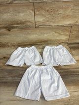 Three pairs of white kids' shorts with elastic waistbands on wood floor, perfect for baby or toddler clothing resale.