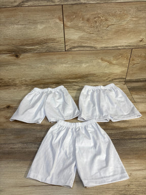 Three pairs of white kids' shorts with elastic waistbands on wood floor, perfect for baby or toddler clothing resale.