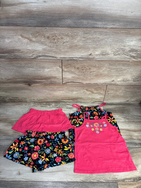 Flat lay of girls' 4-piece set: pink embroidered tank, black floral halter, floral shorts, pink skort on wood floor