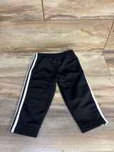 Flat lay of Adidas baby black active pants size 12 months showcasing white side stripes and elastic waistband on wood floor