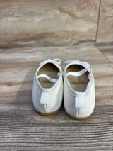 Rear view of Cat & Jack Nora white slip-on ballet flats showing heel pull tab, elastic strap, bow detail and tan sole on light wood background