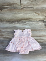 Flat lay of newborn pink ribbed bodysuit dress with flutter sleeves and dragonfly print skirt on wood plank background