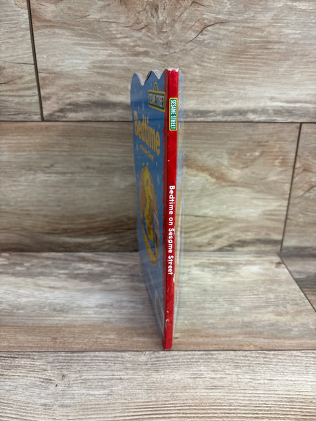 Side view of Bedtime on Sesame Street hardcover book showcasing its red spine and blue cover on a wood grain background