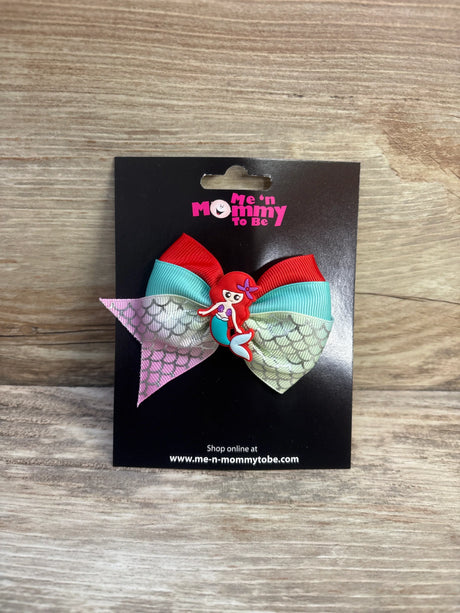 Front view of red and turquoise mermaid applique hair bow with iridescent mermaid-scale tails and mermaid charm on black card