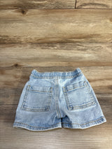 Back view of light blue toddler jean shorts showing elastic waistband and two patch pockets on wood background