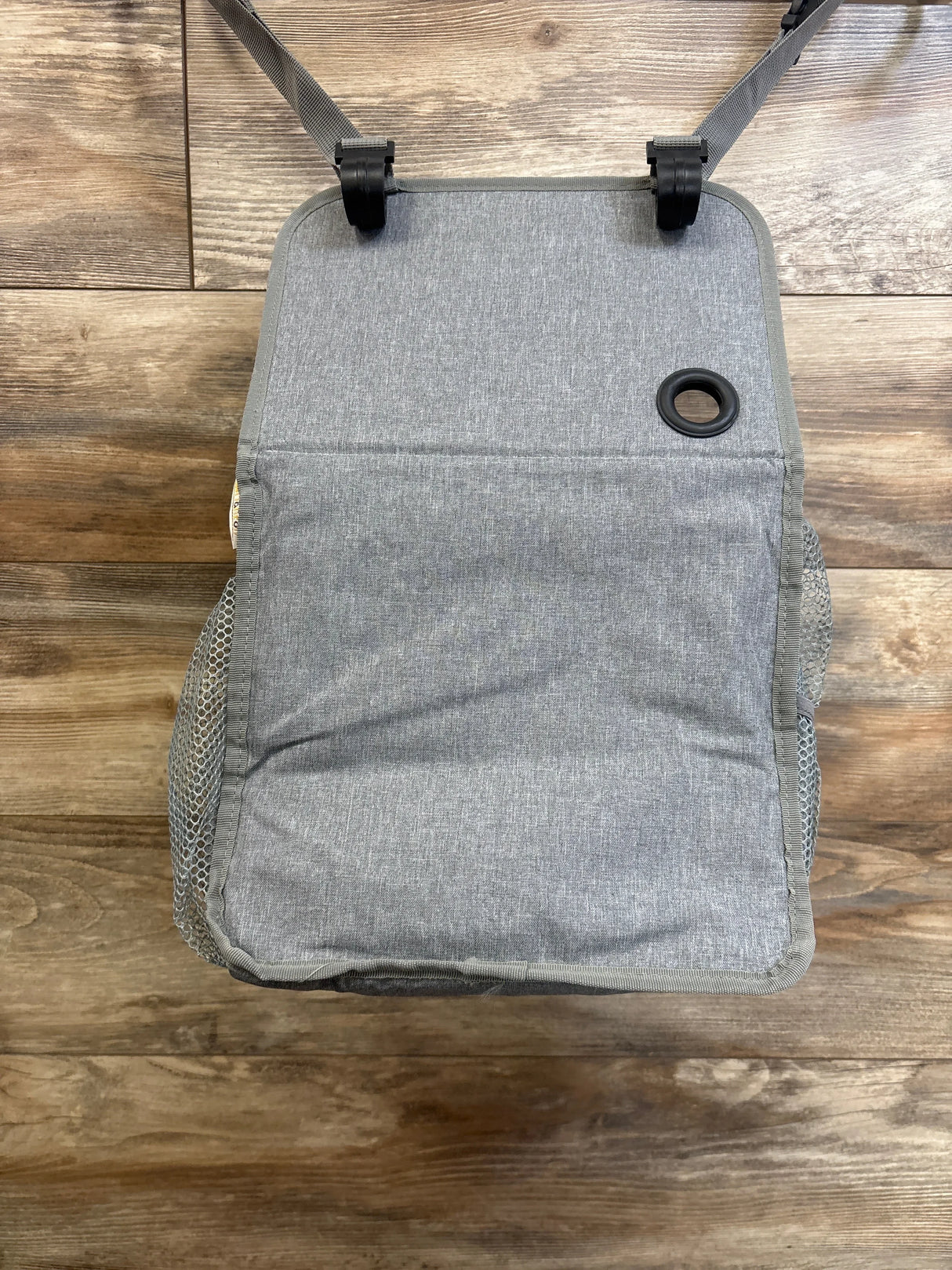 Overhead view of Maliton hanging diaper caddy organizer in grey showing closed front flap, hanging straps with clips, and mesh side pockets on wood floor