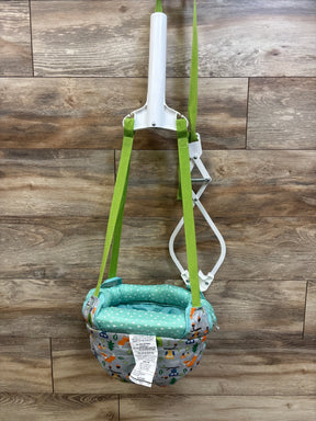 Front view of Evenflo Exersaucer Door Jumper showcasing green straps, white frame, and forest animal print seat against wood background