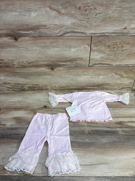 Pink baby outfit with lace ruffle details on sleeves and pant legs on wooden floor