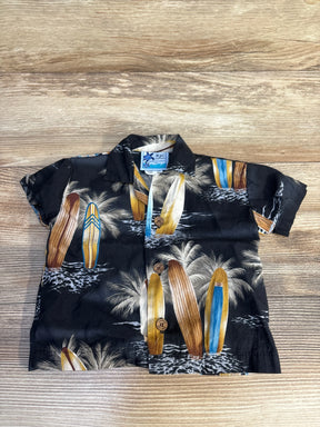 Flat lay of infant black RJC Hawaiian button-up shirt showing surfboard and palm tree print and wooden buttons on wood background