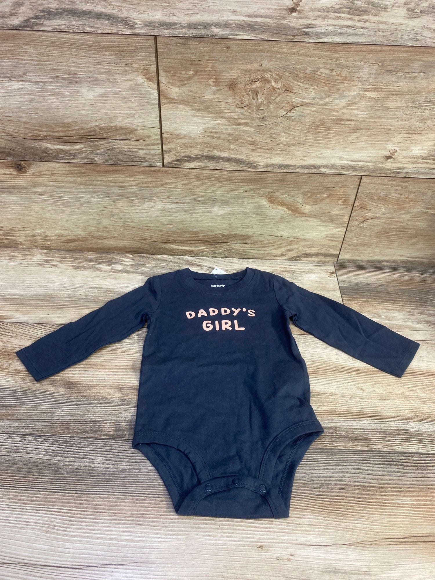 Front view of Carter’s Daddy’s Girl long sleeve bodysuit with snap closures on a wood-look floor