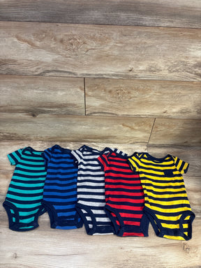 Overhead view of five striped baby bodysuits in navy and assorted colors with snap closures on a wood floor