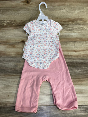 Front view of white floral baby bodysuit with bow paired with pink pants on hanger against wood background