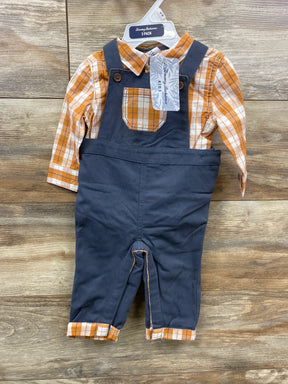 Baby boy outfit with orange plaid shirt and navy blue overalls on wooden background