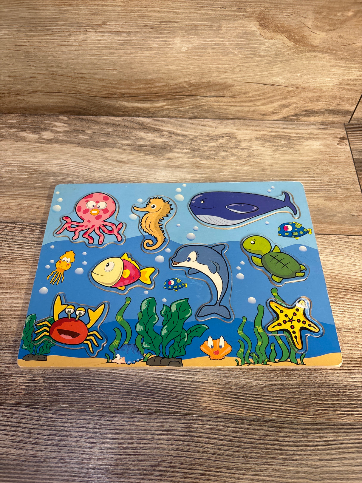 Top-down view of an 8-piece wooden sea puzzle showing colorful cartoon animal pieces on a wood tabletop