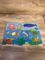 Top-down view of an 8-piece wooden sea puzzle showing colorful cartoon animal pieces on a wood tabletop