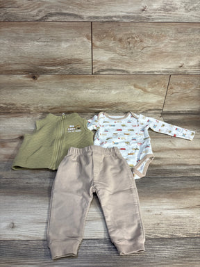 Top view of 3-piece baby set I Dig My Mommy: green quilted vest, vehicle-print long-sleeve bodysuit, beige joggers on wood background
