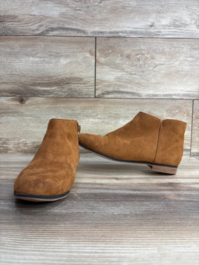 Pair of tan suede ankle boots with side zipper on wooden floor and background