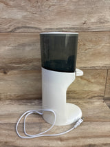 Front view of Baby Brezza Instant Bottle Warmer showcasing white housing, dark translucent upper chamber, and power cord on a wood surface
