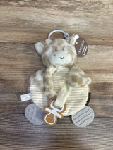 Plush giraffe baby toy with teething rings and rattle on wood background