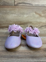 Lavender glitter baby shoes with floral embellishments on wooden floor