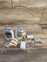 Front view of VTech DM221 baby monitor showing parent unit with LCD, baby unit and power adapters on wood background