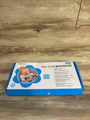 IGRATENS toy for bouncer with smiling baby image on box, blue and white packaging on wooden floor