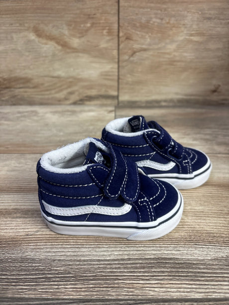 Three-quarter view of navy Vans SK8-Mid V sneakers showcasing white side stripes and hook-and-loop straps on a wood surface