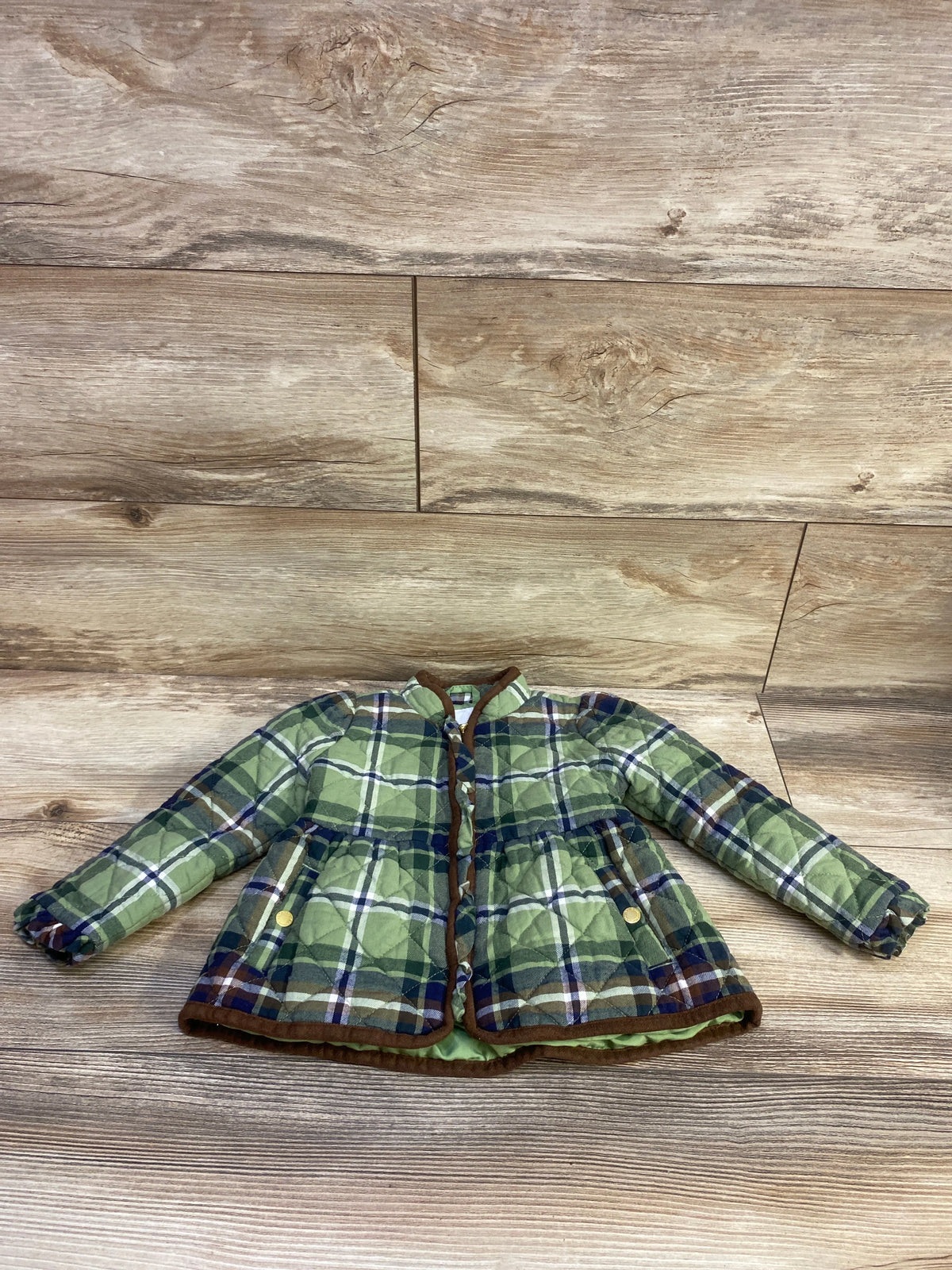 Front view of Janie and Jack The Equestrian plaid jacket showcasing green plaid quilting and front pockets on a wood floor