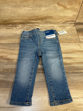 Flat lay of NWT Old Navy skinny jeggings in light blue wash denim with pull on waistband and hangtags on wood plank floor