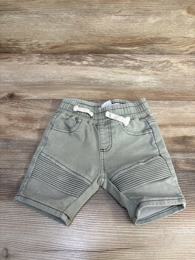 Front view of green Cotton On Baby moto shorts 6-12m showing ribbed knee panels and drawstring waist on wood background