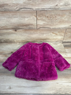 Plush pink faux fur kid's jacket laid on wooden floor