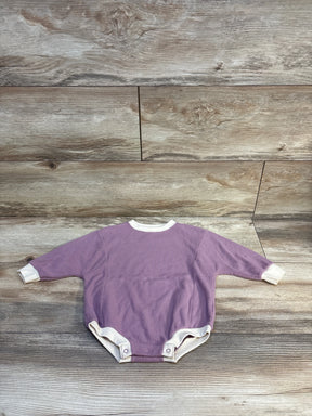 Purple ribbed baby onesie with white trim, laid flat on wood floor — ideal for infant clothing resale.
