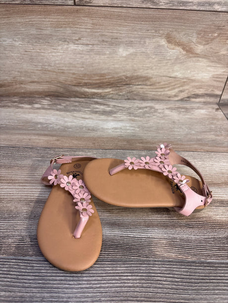 Top view of toddler pink Beverly Hills Polo Club sandals with daisy flower T-strap, tan footbed, and ankle buckle on wood