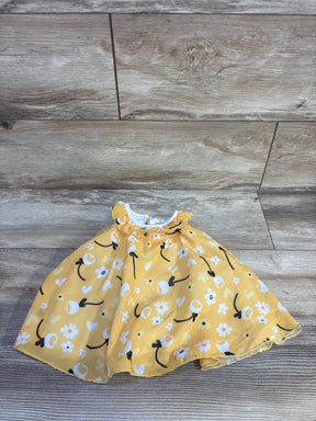 Flat lay of yellow Baby Starters tulle bodysuit dress showing white floral print and ruffled collar on light wood background
