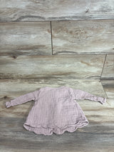 Flat lay of Jamie Kay Lila muslin blouse in rose smoke with crinkled texture, scalloped hem, and ruched cuffs on wood