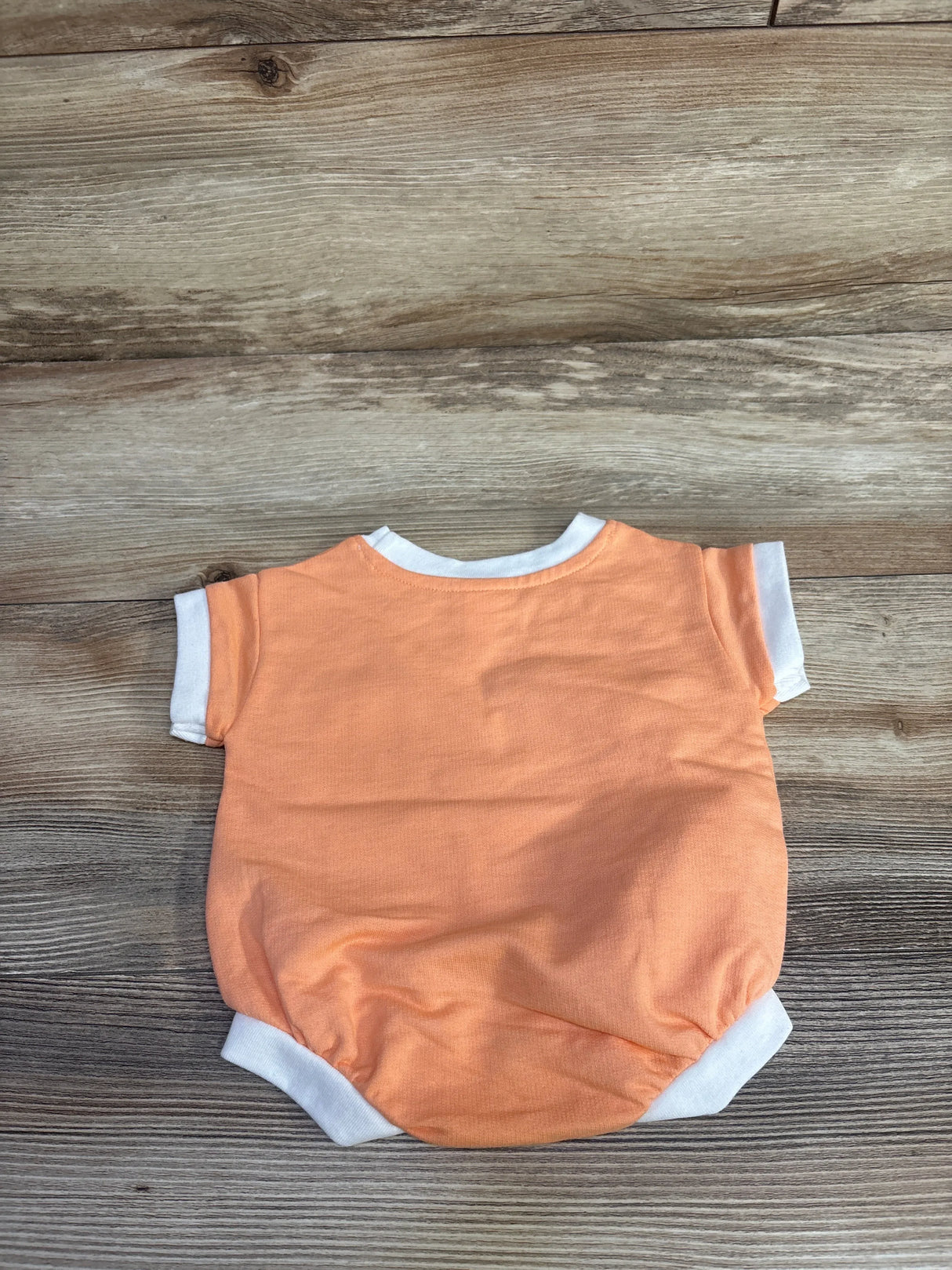 Back view flat lay of newborn Cat and Jack terry romper in orange with white trim and short sleeves on wood background