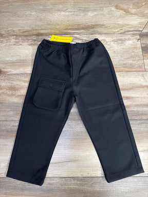 Black children's pants with elastic waistband and flap pocket on wood floor background