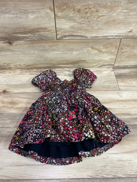 Front view of Baby Gap smocked puff sleeve dress showing floral print on a wood-look floor