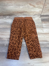 Flat lay of brown leopard print Okie Dokie jogger pants showing elastic waistband and cuffed ankles on light wood background